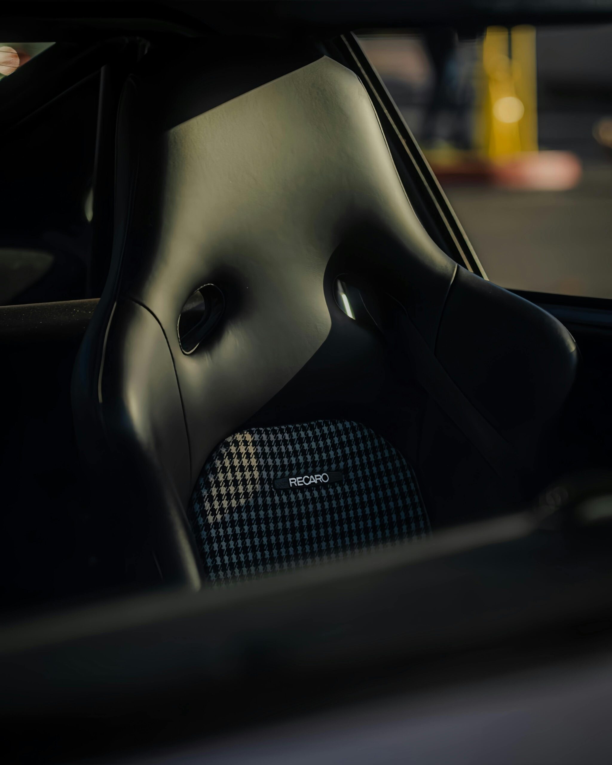 Close-up of a luxury car's black Recaro seat, showcasing premium design.